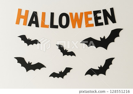 Halloween wall decor featuring black bats and large orange letters on a simple white background. concept of festive home decorations, spooky ambiance, seasonal celebration. 128551216
