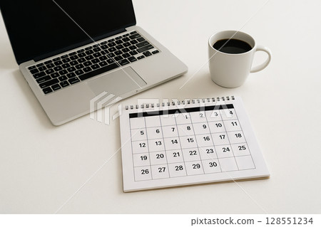 Organized workspace with laptop, calendar, and coffee cup on simple desk for efficient planning. concept of productivity, office essentials, modern work environment 128551234