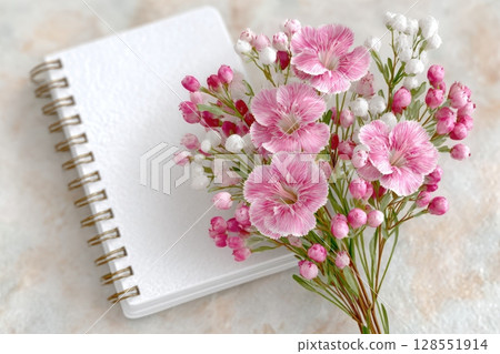 White notebook mockup with pink and white flowers arranged on a marble surface, perfect for feminine stationery or branding design presentations. 128551914