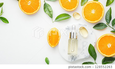 Flat lay of a glass skincare serum bottle with citrus slices and gel drops on white background, styled with greenery and marble accents in a modern, organic beauty concept. 128552263