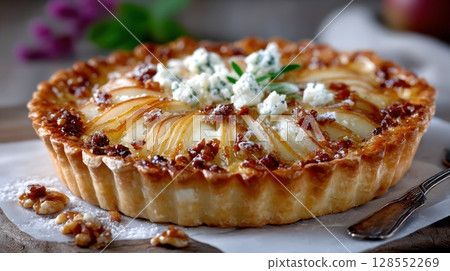 Caramelized pear tart with goat cheese and nuts, served rustic-style on parchment paper with vintage props and soft lighting. Caramelized pear tart with goat cheese and nuts, served rustic-style on parchment paper with vintage props and soft lighting. 128552269