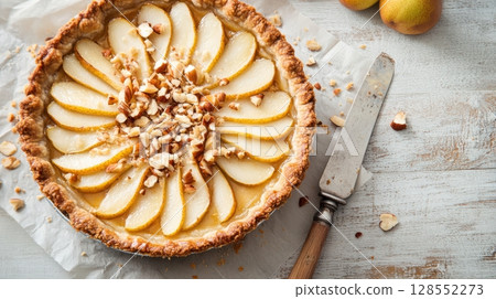Rustic pear and goat cheese pie topped with nuts and golden edges, styled on parchment with cozy artisan details and warm natural lighting. Rustic pear and goat cheese pie topped with nuts and golden edges, styled on parchment with cozy artisan details and warm natural lighting. 128552273
