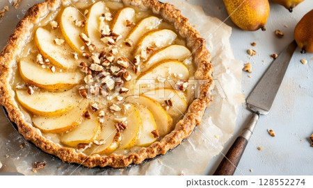 Rustic pear and goat cheese pie topped with nuts and golden edges, styled on parchment with cozy artisan details and warm natural lighting. 128552274