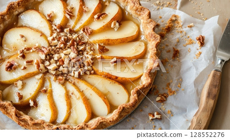Rustic pear and goat cheese pie with golden crust, layered pear slices, crumbled nuts, and cozy artisan presentation on parchment paper 128552276