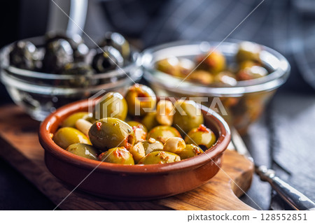 Tapas. Flavored pickled olives in bowl on cutting board. 128552851