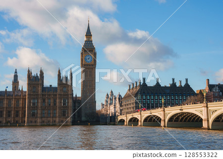 View of Big Ben and the Houses of Parliament in London, England, with Westminster Bridge and a red double decker bus crossing the River Thames. View of Big Ben and the Houses of Parliament in London, England, with Westminster Bridge and a red double decker bus crossing the River Thames. 128553322