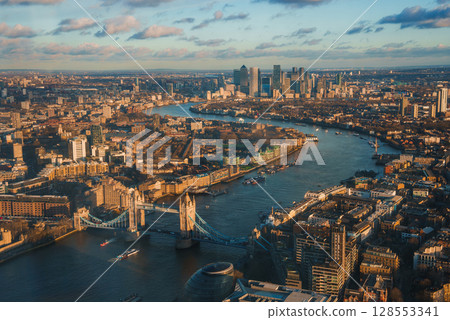 Aerial view of London's Tower Bridge over the River Thames during Christmas. The cityscape features historic architecture and Canary Wharf skyscrapers. Aerial view of London's Tower Bridge over the River Thames during Christmas. The cityscape features historic architecture and Canary Wharf skyscrapers. 128553341