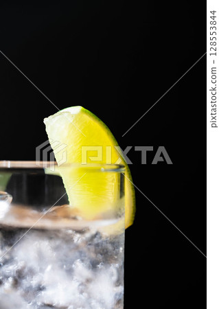 [Cocktail ingredients] A delicious-looking gin and tonic poured into a glass with ice on a black background [Drink ingredients] 128553844