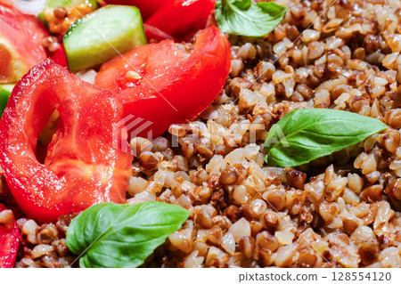 Healthy food without meat with buckwheat and a salad of chopped tomatoes, cucumbers, onions and basil leaves. The photo is suitable for the topic of healthy lifestyle and healthy eating 128554120