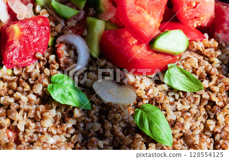 Healthy food without meat with buckwheat and a salad of chopped tomatoes, cucumbers, onions and basil leaves. The photo is suitable for the topic of healthy lifestyle and healthy eating 128554125