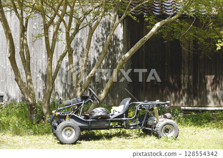 An unused single-seater cart placed in front of an old house 128554342