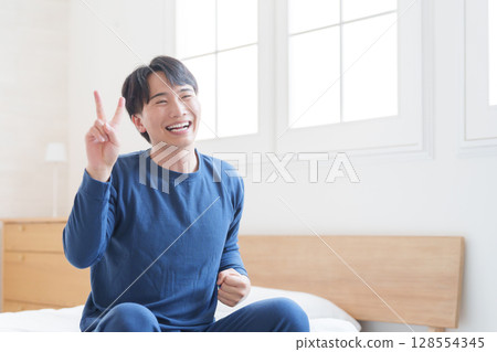 男人在床上做出和平手勢 128554345