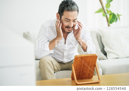 A middle-aged man in his 50s checking his skin in the mirror 128554548