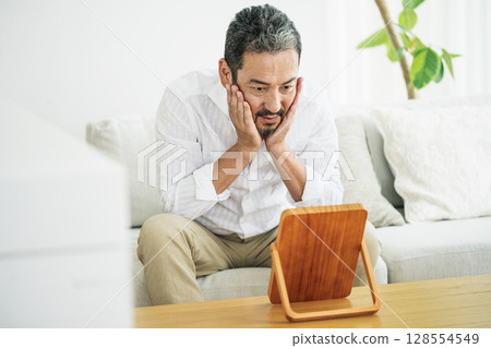 A middle-aged man in his 50s checking his skin in the mirror 128554549