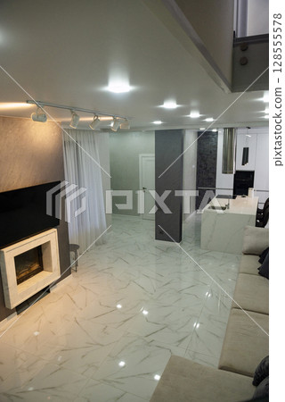 A room with a kitchen area and a fireplace. 128555578
