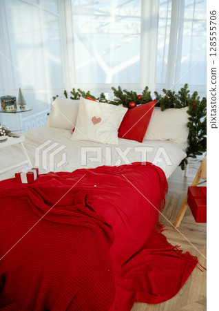 Bed with New Year's decor. There is a red bedspread on the bed. 128555706