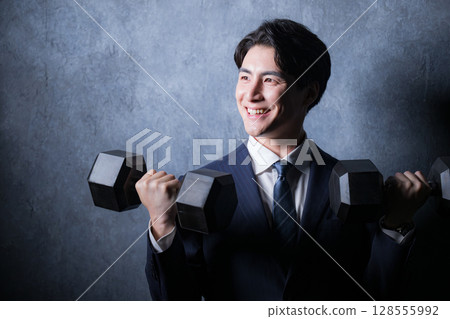 一個穿西裝的男人用啞鈴進行肌肉訓練 128555992