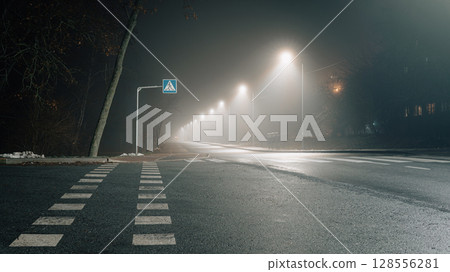 Empty Foggy Road with Streetlights on a Misty Night Empty Foggy Road with Streetlights on a Misty Night 128556281