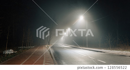 Foggy Night Street with Bicycle Lane and Streetlights 128556522