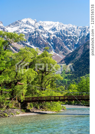A spectacular view of Kamikochi: Kappa Bridge and the Hotaka mountain range in the season of fresh greenery 128556538