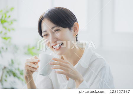 Middle woman drinking coffee in the living room 128557387