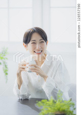 Middle woman drinking coffee in the living room 128557390