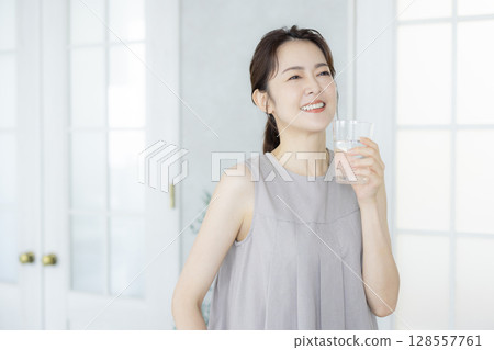 Middle-aged woman drinking water in the kitchen 128557761