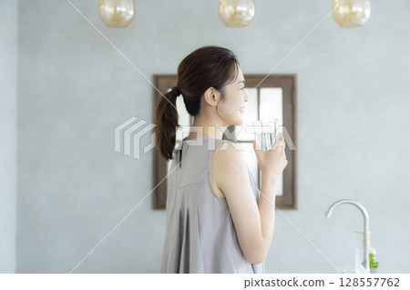 Middle-aged woman drinking water in the kitchen 128557762
