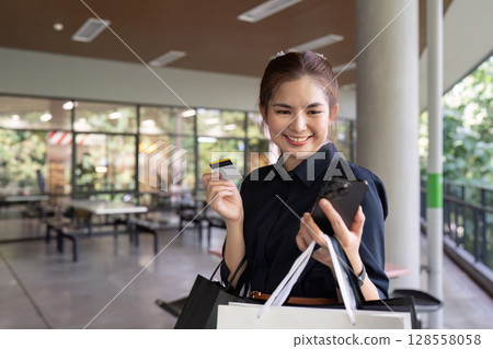 Young Woman Shopping with Credit Card and Smartphone in Modern Mall Young Woman Shopping with Credit Card and Smartphone in Modern Mall 128558058