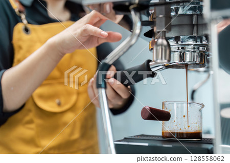 Barista Preparing Fresh Espresso with Professional Coffee Machine in Modern Cafe Barista Preparing Fresh Espresso with Professional Coffee Machine in Modern Cafe 128558062