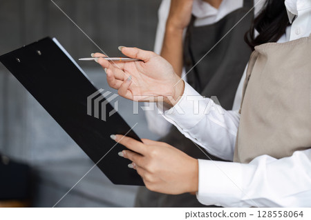 Business Meeting with Colleagues Reviewing Documents and Using Calculator at Office Desk Business Meeting with Colleagues Reviewing Documents and Using Calculator at Office Desk 128558064