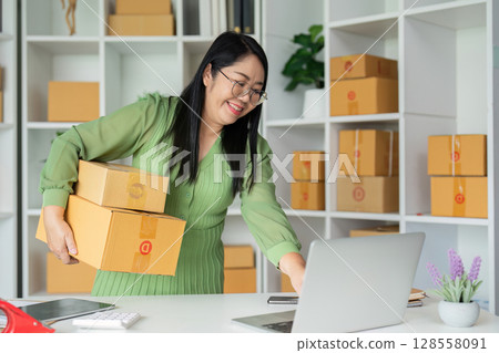 Small Business Owner Managing Online Orders and Inventory in a Modern Office Space Small Business Owner Managing Online Orders and Inventory in a Modern Office Space 128558091