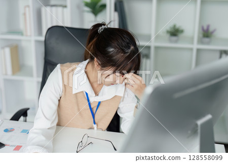 Stressed Office Worker Feeling Unwell at Desk with Headache and Fatigue in Modern Workplace Environment Stressed Office Worker Feeling Unwell at Desk with Headache and Fatigue in Modern Workplace Environment 128558099