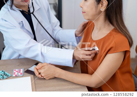 Female Doctor Using Stethoscope to Examine Middle-Aged Woman During Medical Checkup in Clinic 128558292