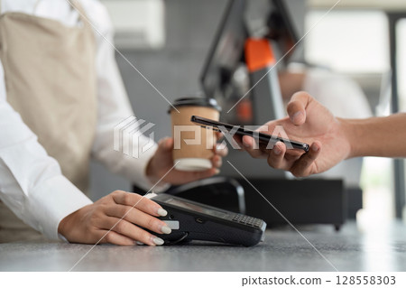 Customer Making Contactless Payment with Smartphone at Coffee Shop Counter 128558303