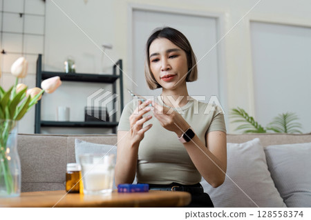 Woman Preparing Medication at Home, Focused on Health and Wellness in a Modern Living Room Setting 128558374