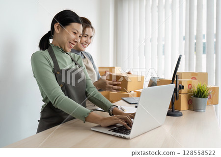 Small Business Owners Working Together in Modern Office with Laptop and Packages 128558522
