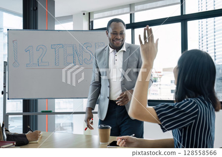 Engaged Student Raising Hand in Modern Classroom During Interactive Learning Session with Teacher Engaged Student Raising Hand in Modern Classroom During Interactive Learning Session with Teacher 128558566