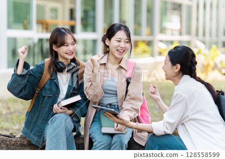 Group of Happy University Students Studying and Socializing Outdoors on Campus 128558599