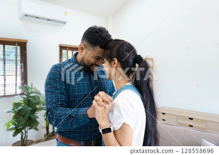 Happy Couple Dancing Together in Living Room with Natural Light and Modern Decor Happy Couple Dancing Together in Living Room with Natural Light and Modern Decor 128558696