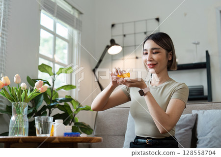 Young Woman Taking Medication at Home in a Bright Living Room with Natural Light and Indoor Plants 128558704