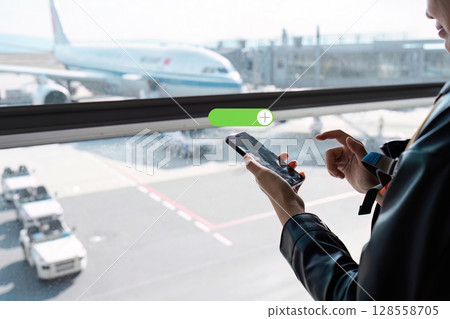 Business Traveler Using Smartphone at Airport Terminal with Airplane in Background 128558705