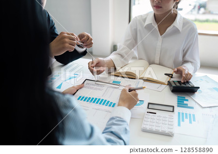 Business Team Analyzing Financial Data and Chart in a Modern Office Setting Business Team Analyzing Financial Data and Chart in a Modern Office Setting 128558890