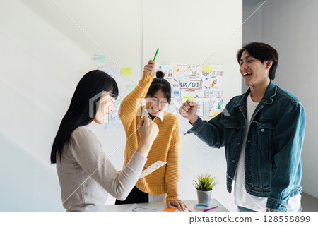 Creative Team Collaborating on UX UI Design Project in Modern Office Environment 128558899