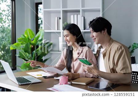 Happy Couple Managing Finances and Saving Money Together at Home with Laptop and Documents 128559151