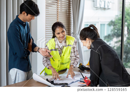 Team of Young Architect collaboration on a Project in a Modern Office Setting with Blueprint and Construction Tools 128559165