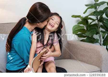 Loving Mother and Daughter Sharing a Happy Moment on the Couch in a Modern Home Setting Loving Mother and Daughter Sharing a Happy Moment on the Couch in a Modern Home Setting 128559169