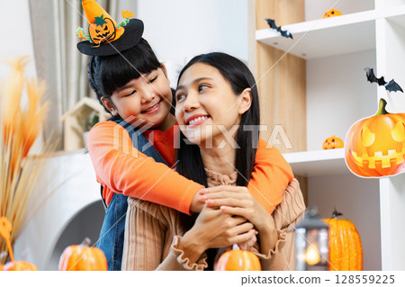 Mother and Daughter Celebrating Halloween with Pumpkins and Decorations in a Festive Home Setting Mother and Daughter Celebrating Halloween with Pumpkins and Decorations in a Festive Home Setting 128559225