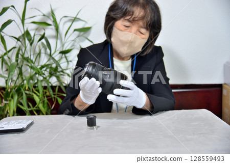 Image of an appraiser evaluating a camera lens 128559493