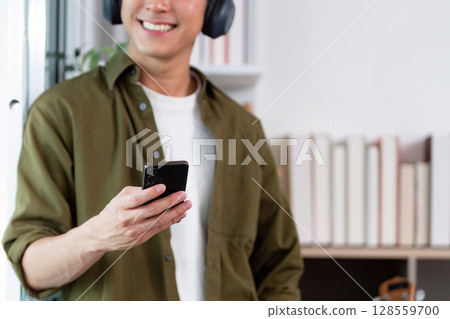 Work from Home: Smiling man checking smartphone while relaxing Work from Home: Smiling man checking smartphone while relaxing 128559700